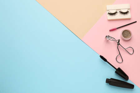 Flat lay composition with eyelash curler, makeup products and accessories on color background. Space...