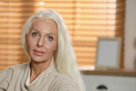 Portrait of elegant mature woman at home. Space for text