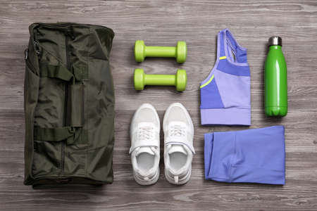 Gym bag and sports equipment on wooden background, flat layの写真素材