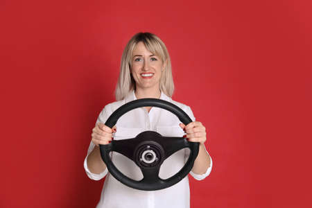 Happy woman with steering wheel on red backgroundの写真素材