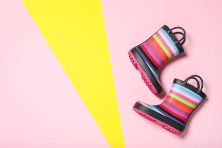 Pair of striped rubber boots on color background, top view. Space for textの写真素材