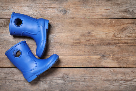 Blue rubber boots on wooden background, top view. Space for textの写真素材