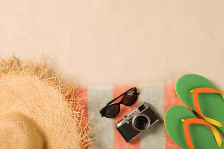 Beach towel, hat, sunglasses, camera and flip flops on sand, flat lay. Space for textの写真素材