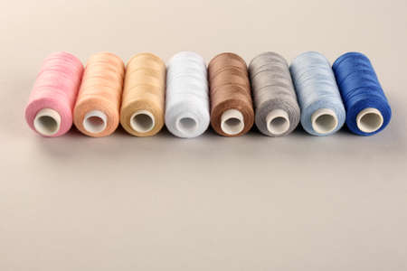 Different sewing threads on light grey background. Space for text