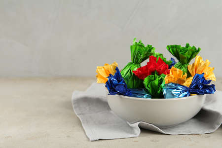 Candies in colorful wrappers on light beige table, space for textの写真素材