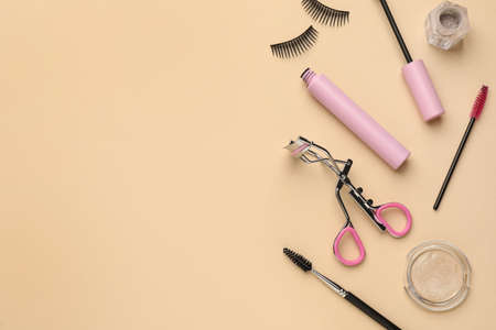 Flat lay composition with eyelash curler, makeup products and accessories on beige background. Space for textの写真素材