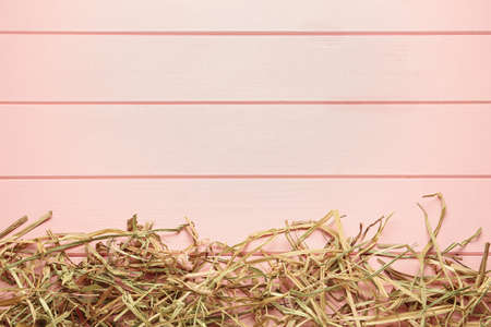 Heap of dried hay on pink wooden background, flat lay. Space for textの写真素材