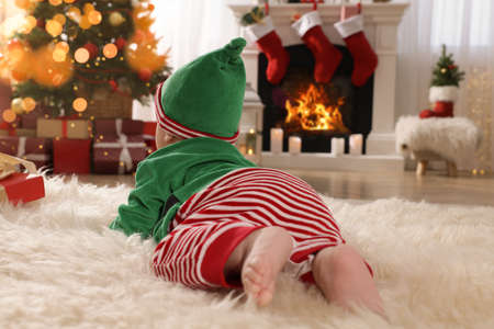 Baby wearing cute elf costume in room decorated for Christmasの写真素材