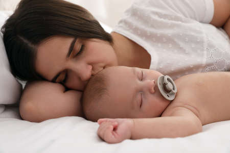 Mother with her cute baby sleeping in bed