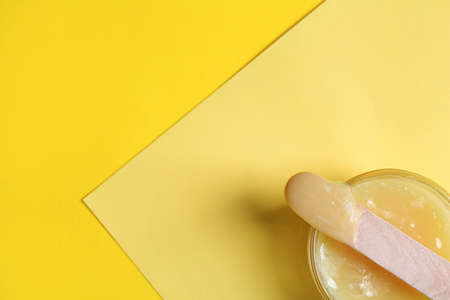 Spatula with wax on yellow background, top view. Space for textの写真素材