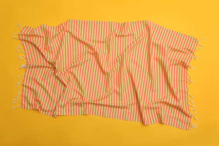 Crumpled striped beach towel on yellow background, top viewの写真素材