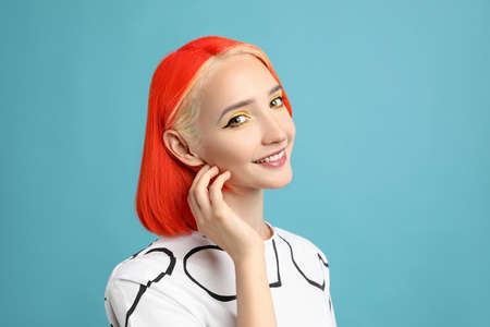 Beautiful young woman with bright dyed hair on turquoise backgroundの写真素材