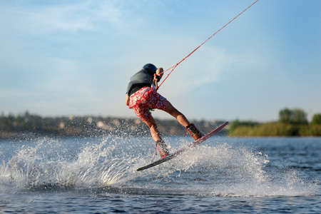 Teenage wakeboarder doing trick on river. Extreme water sportの写真素材