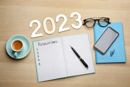 Making resolutions for 2023 new year. Flat lay composition with notebook on wooden tableの写真素材