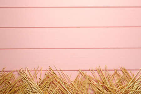 Heap of dried hay on pink wooden background, flat lay. Space for textの写真素材