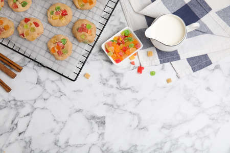 Unbaked cookies with candied fruits on white marble table, flat lay. Space for textの写真素材