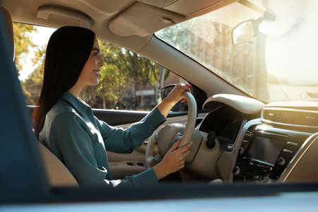 Beautiful young driver sitting in modern car