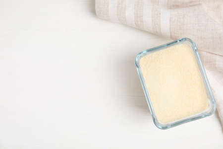 Gelatin powder in glass bowl on white table, top view. Space for text