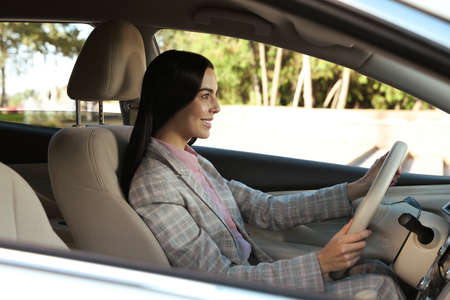 Beautiful young driver sitting in modern car