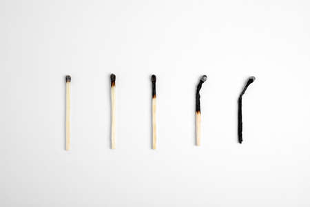 Different stages of burnt matches on white background, flat lay