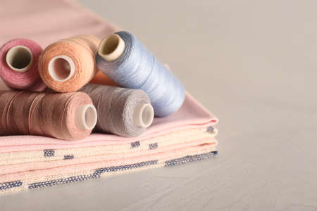 Set of color sewing threads on light grey table, space for textの写真素材