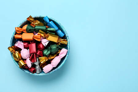 Candies in colorful wrappers on light blue background, top view. Space for textの写真素材