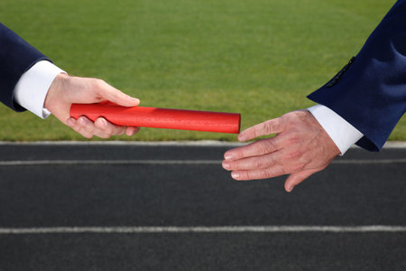 Businessman passing baton to his partner outdoors, closeupの写真素材