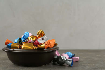 Candies in colorful wrappers on gray table, space for text