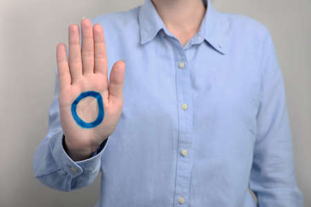 Woman showing blue circle drawn on palm against light gray background, closeup. World Diabetes Day