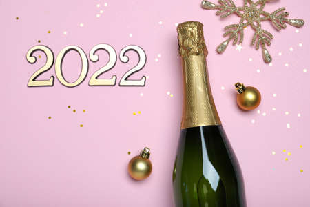 Happy New Year 2022! Flat lay composition with bottle of sparkling wine on pink background, space...