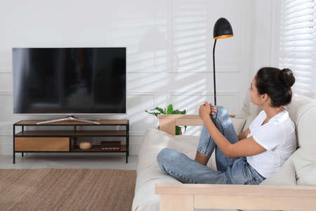 Woman watching television at home. Living room interior with TV on stand
