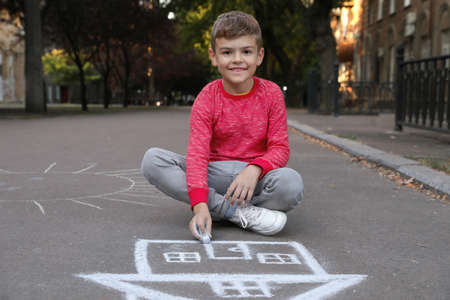 Child drawing house with chalk on asphaltの写真素材