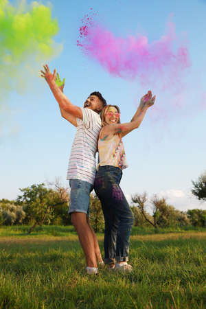 Happy couple with colorful powder dyes outdoors. Holi festival celebrationの写真素材