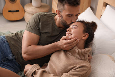 Lovely couple enjoying each other on bed at home