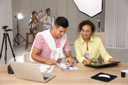 Professional retoucher with colleague working at desk in photo studioの写真素材