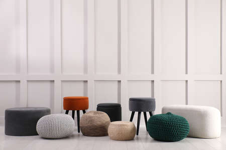 Different stylish poufs and ottomans near light wallの写真素材