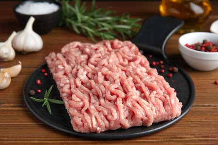 Raw chicken minced meat with spices and rosemary on wooden table, closeupの写真素材