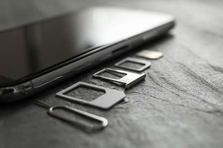SIM card, mobile phone and ejector tool on gray table, closeupの写真素材