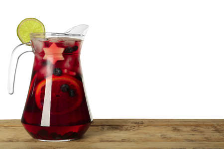 Glass jug of Red Sangria on wooden table against white background. Space for textの写真素材