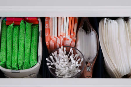 Open cabinet drawer with menstrual pads, tampons and cotton buds, above viewの写真素材