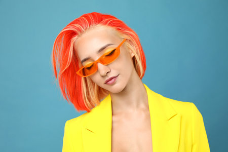 Beautiful young woman with bright dyed hair on turquoise backgroundの写真素材