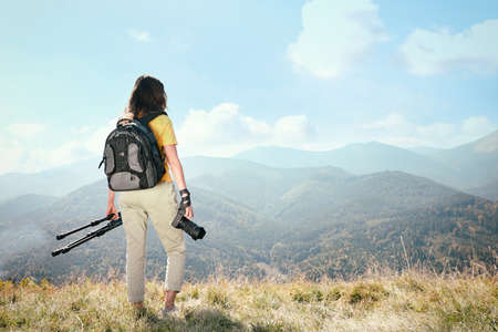 Professional photographer with modern camera and tripod in mountains, back view. Space for textの写真素材