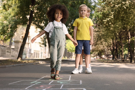 Little children playing hopscotch drawn with chalk on asphalt outdoorsの写真素材