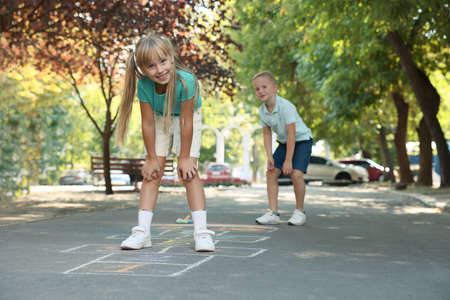 Little children playing hopscotch drawn with chalk on asphalt outdoorsの写真素材