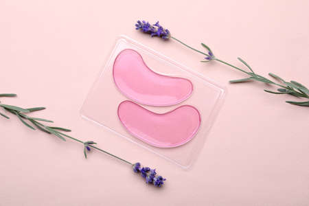 Package with under eye patches and lavender flowers on light pink background, flat lay. Cosmetic productの写真素材