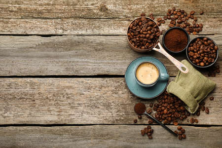 Coffee beans, powder and cup of drink on wooden table, flat lay. Space for textの写真素材