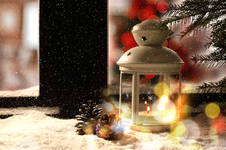 Lantern with candle and pine cones near window outdoors. Christmas eveの写真素材