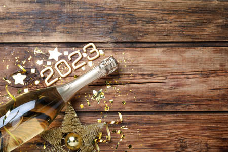 Happy New Year 2023! Flat lay composition with bottle of sparkling wine on wooden table, space for...