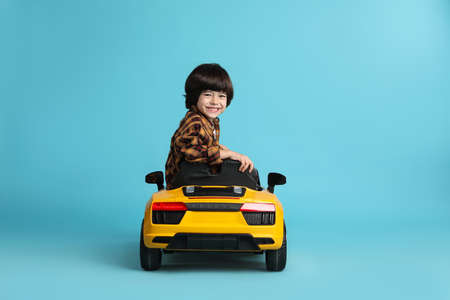Little child driving yellow toy car on light blue backgroundの写真素材