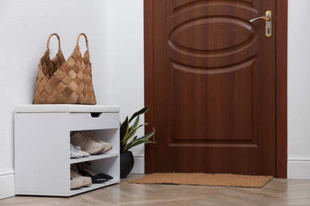 Shelving unit with shoes, houseplant and door mat in hallの写真素材